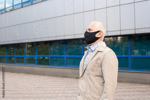 Senior man wearing protective mask in city near office buildings outbreak of viral disease coronavirus covid-2019