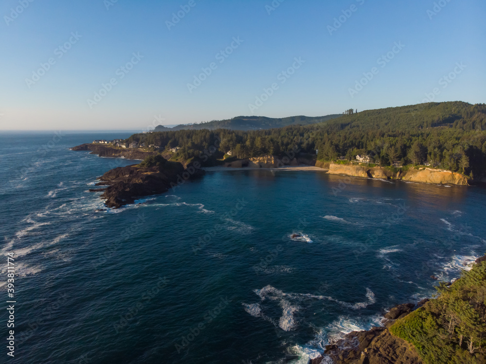 Fototapeta premium Aerial view of forest rocky coast and blue ocean waves at warm sunny day. Fantastic nature. Travel and discover concept. Wallpaper design.