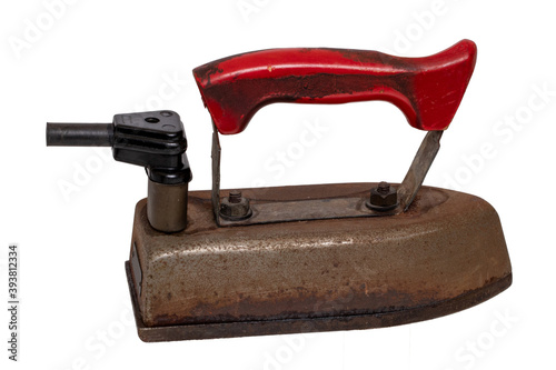 Old iron isolated. Close-up of a professional old rusty electric tailor iron with a red handle and a vintage power plug isolated on a white background. Macro photgraph.