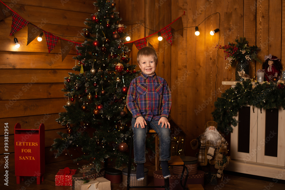 Boy sitting near Christmas tree. Merry Christmas and Happy New Year.