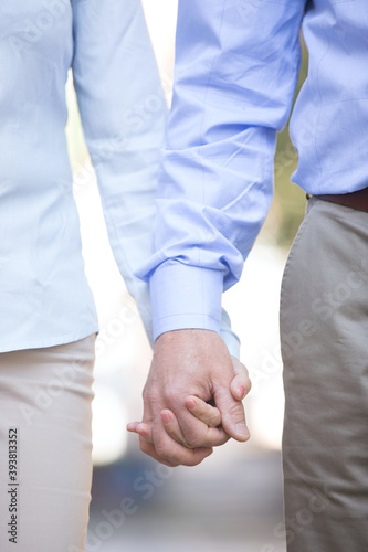 Midsection of middle-aged couple holding hands outdoors