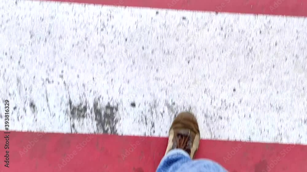 Close-up top view of the feet of a man walking on city roads and ...