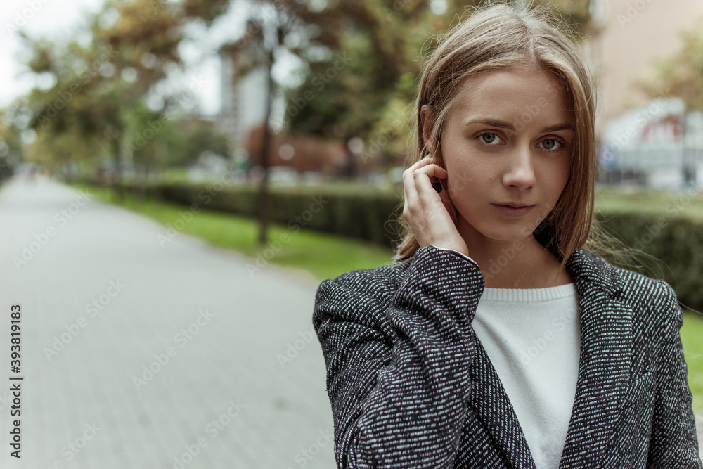 close up portrait beauty blonde young female model dressed in grey warm overcoat posing at camera on the city boulevard close up portrait beauty blonde young female model dressed in grey warm overcoat posing at camera on the city boulevard