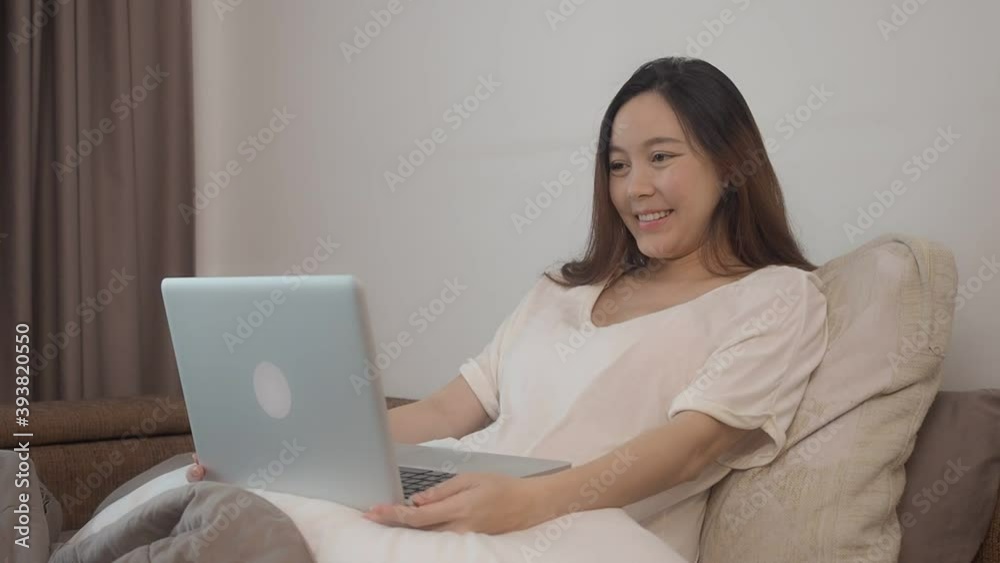 asian woman in casual wear talking with friend on video call via laptop computer in bedroom. female on bed waving hand to webcam. asian woman in casual wear talking with friend on video call via laptop computer in bedroom. female on bed waving hand to webcam.