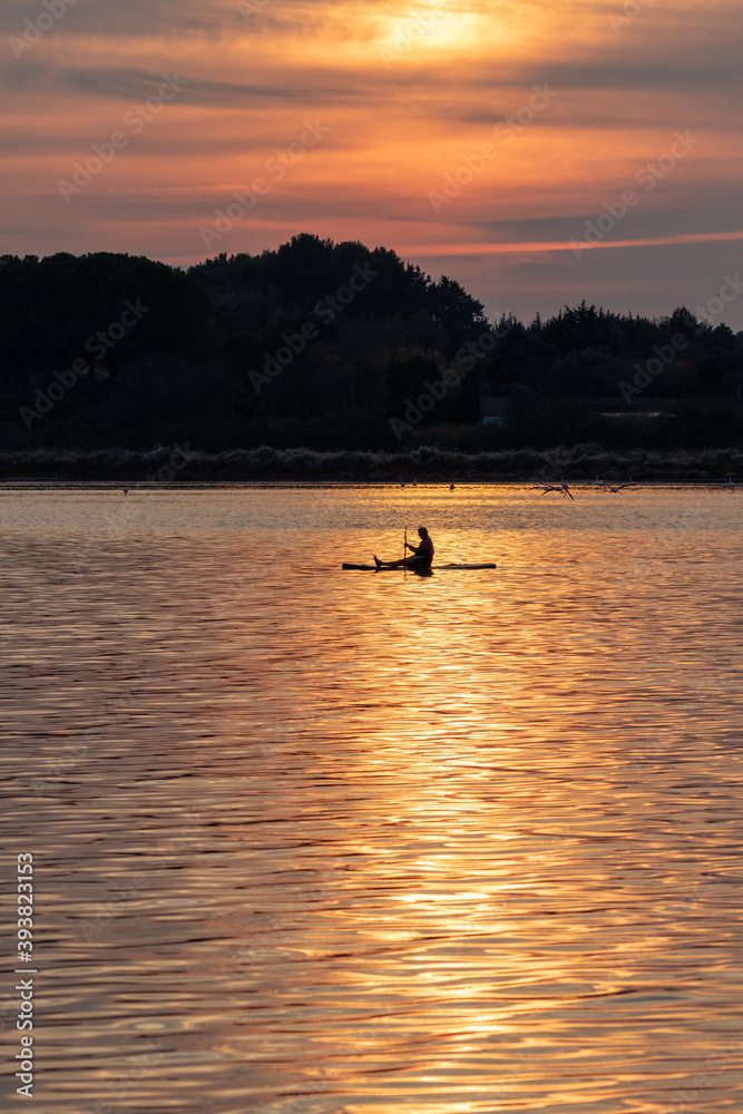 Rameur lors d'un coucher de soleil à la Conque dans l'étang de Thau à Mèze dans le département de l'Hérault en région Occitanie Rameur lors d'un coucher de soleil à la Conque dans l'étang de Thau à Mèze dans le département de l'Hérault en région Occitanie