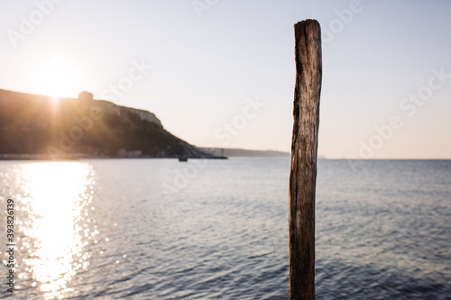 Kavarna, Bulgaria - September 5 2016: Log on the boat dock in the morning sun, on the horizon the sunrise, cliff and sea