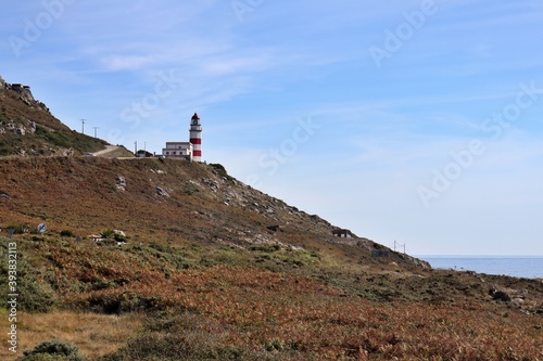 view of a traditional lighthouse on top of a hill on the ocean coast