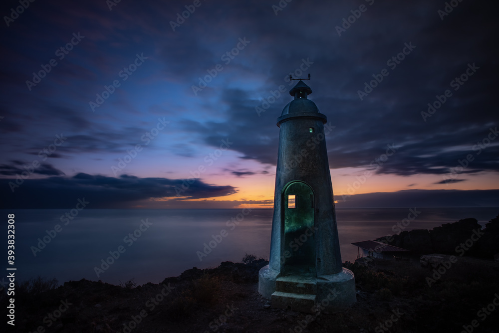 sunset and a small lighthouse by the sea