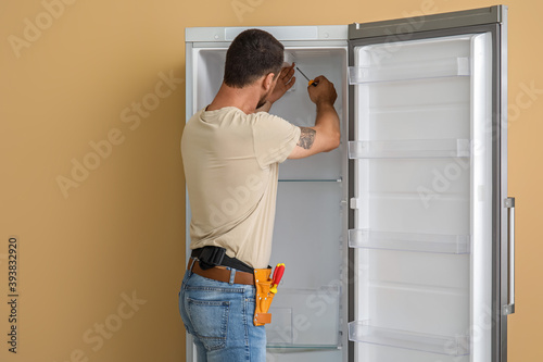 Worker repairing fridge on ...