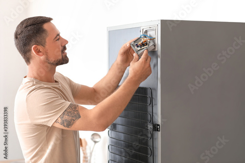 Worker repairing fridge in kitchen