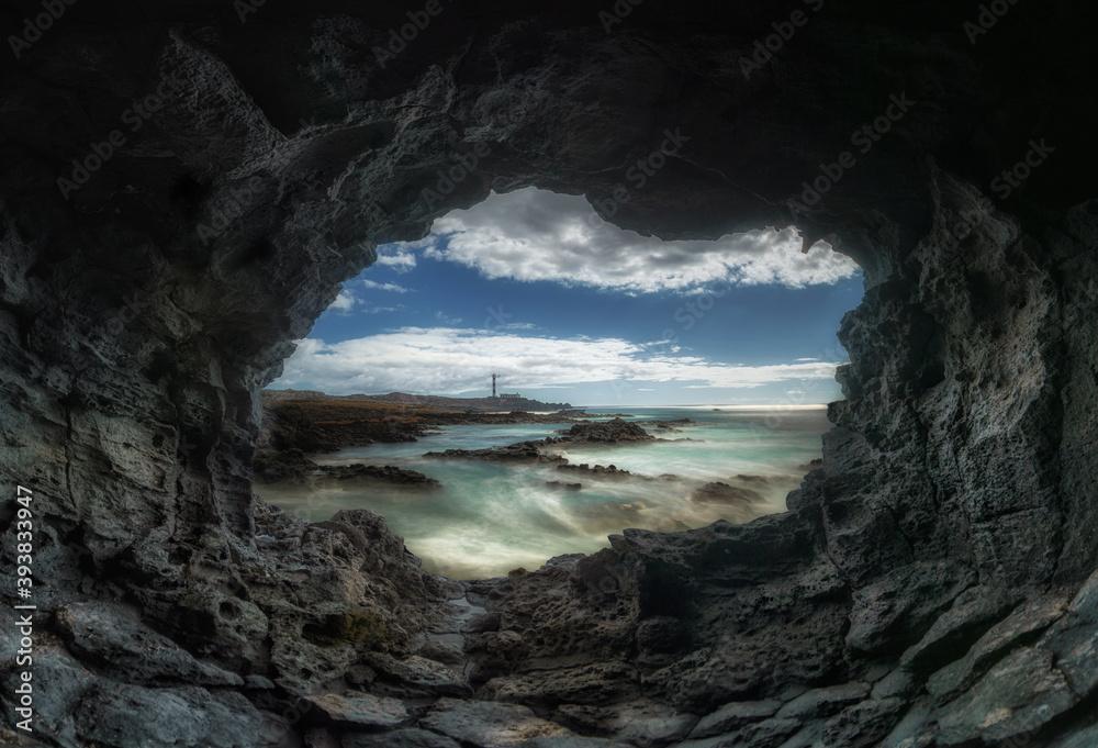 view of a lighthouse and the sea from inside a cave
