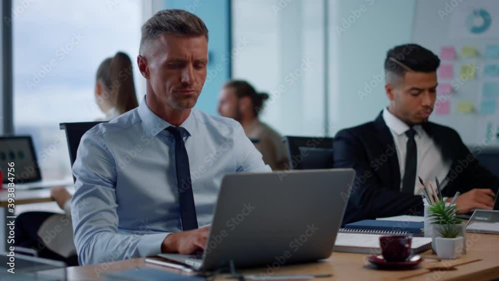 Businessman working on laptop in office. Male professional typing on laptop Businessman working on laptop in office. Male professional typing on laptop