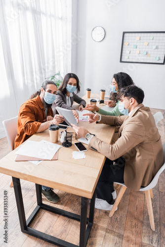 hispanic businesspeople pointing with finger at document during meeting in boardroom