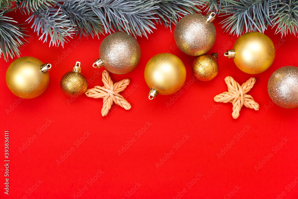 Golden Christmas balls decoration and fir branch on a red background with copy space. New Year composition. Flat lay, top view. Minimalistic style.