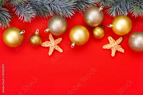 Golden Christmas balls decoration and fir branch on a red background with copy space. New Year composition. Flat lay  top view. Minimalistic style.