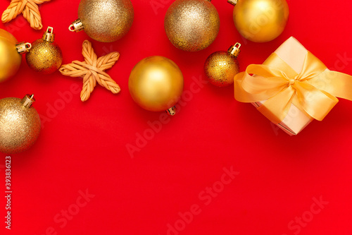 Golden Christmas balls decoration and fir branch on a red background with copy space. New Year composition. Flat lay, top view. Minimalistic style.