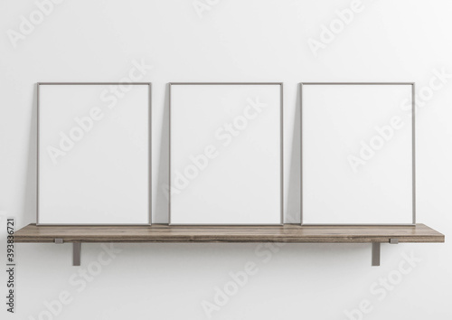 Vertical metal frame mockup. Metal frame poster on a wooden shelf with white wall. 3D illustrations. 3 Frames mockup