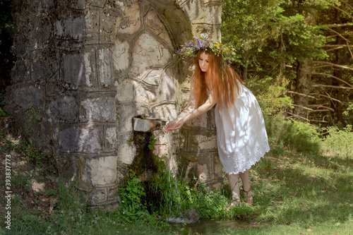 Young woman near the source in the mountains