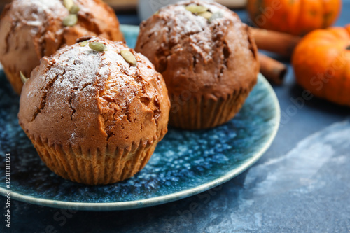 Plate with tasty pumpkin muffins on color background, closeup