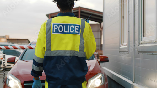 Back view of police officer in uniform with walkie talkie near car checkpoint © TommyStockProject