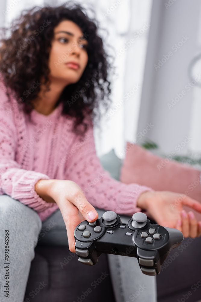 KYIV, UKRAINE - NOVEMBER 16, 2020: gamepad in hand of woman playing video game on blurred background KYIV, UKRAINE - NOVEMBER 16, 2020: gamepad in hand of woman playing video game on blurred background
