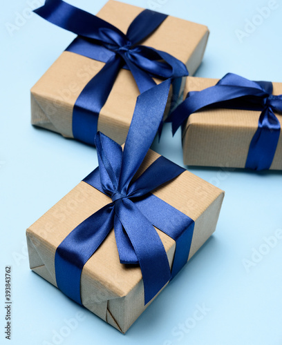 box wrapped in brown paper and tied with a blue silk ribbon with a bow, gift on a blue background