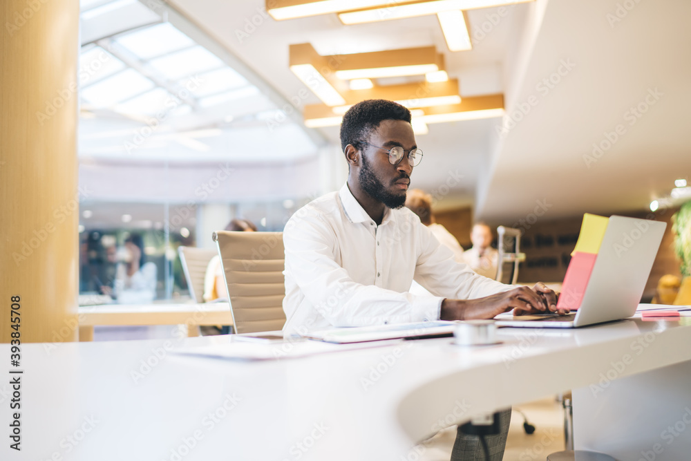 Black man working on laptop in open space office Black man working on laptop in open space office