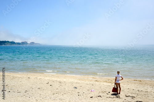 Ravda, Bulgaria. May, 20, 2014. A lonely woman standing near waterfront looks at the seashore with misty clouds covering waves.