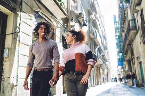 Smiling diverse couple spending time on city street and holding hands