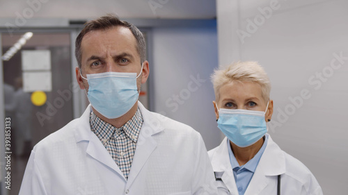 Portrait of emergency department doctors in safety mask and lab coat posing at camera