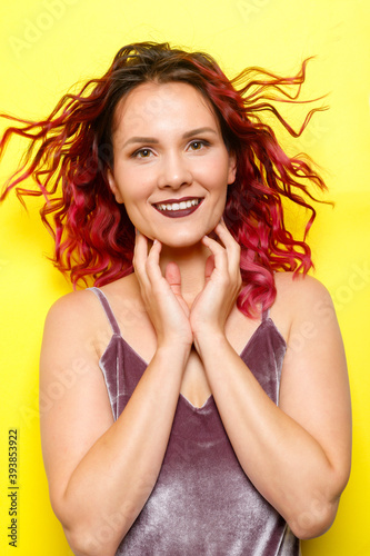 Indoor portrait of excited curly woman with trendy makeup. Ginger caucasian young lady smiling on yellow background. redhead girl with flying curly hair smiling laughing