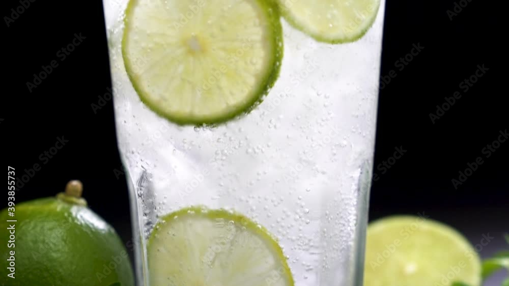 Fresh lime soda in glass drink with sliced lime on black background