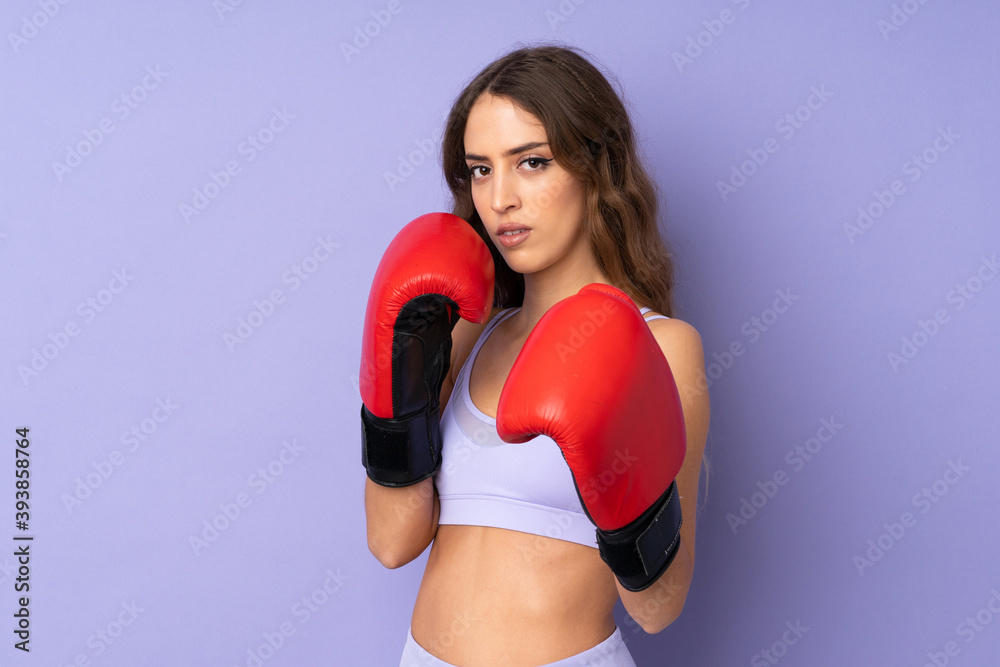 Young sport woman over isolated purple background with boxing gloves