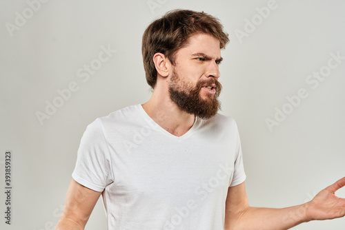 bearded man gesturing with his hands in a white t-shirt aggression light background © SHOTPRIME STUDIO