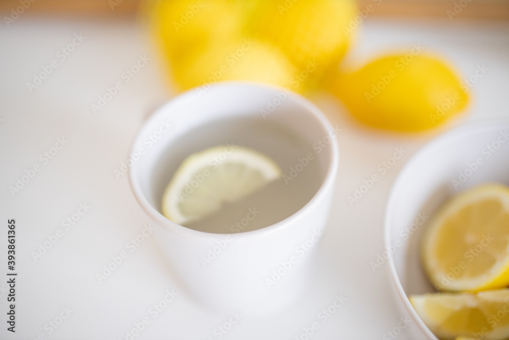 Cup of lemon tea on a white table surrounded by lemons Cup of lemon tea on a white table surrounded by lemons