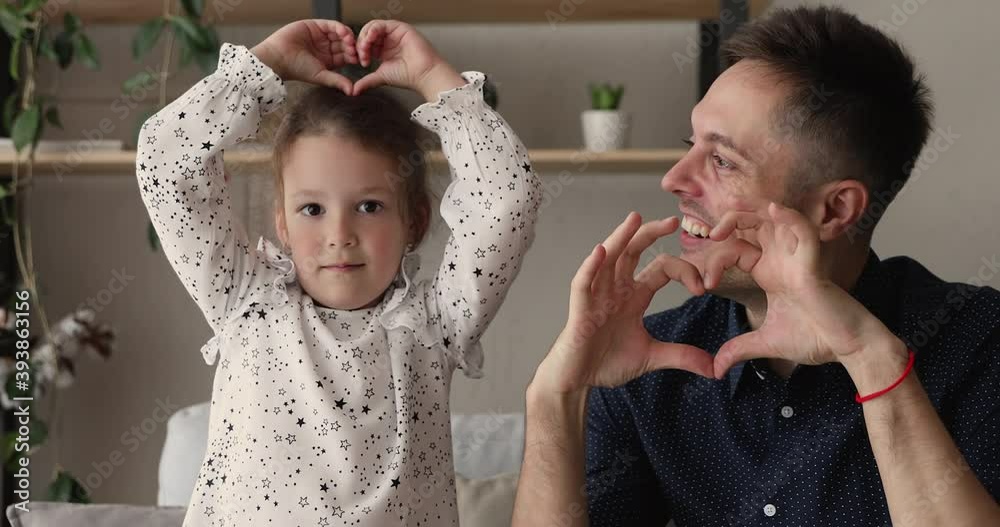 Young father and little 5s adorable daughter smiling looking at camera showing symbol making with fingers heart shape sign of love. Concept of blood donation and save life, volunteering, family bond