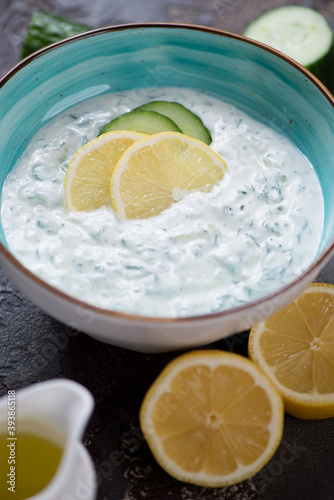 Close-up of a turquoise bowl with tzatziki or greek sauce made of yogurt, cucumber, olive oil and fresh herbs, vertical shot