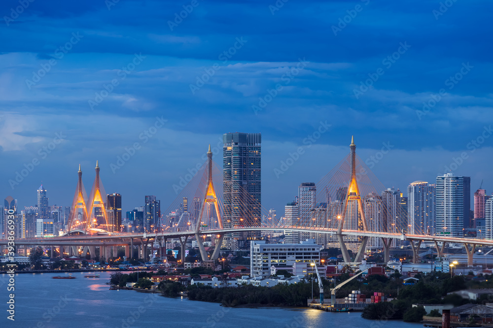 Large suspension bridge over Chao Phraya river at twilight, with city in background