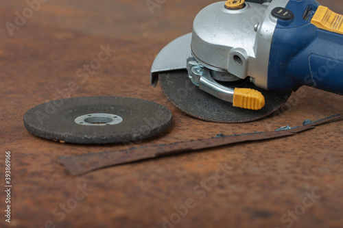 Angle grinder with thinner cut-off disc and grinding disc on old rusty metal sheet.