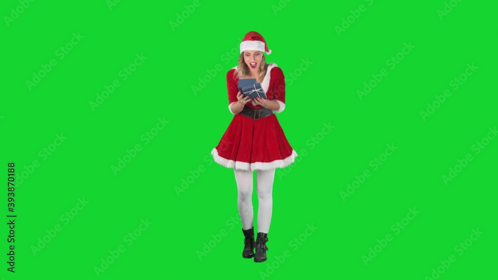 Cheerful young Santa Claus woman opening gift box illuminated by magic light. Full body length on green screen. Cheerful young Santa Claus woman opening gift box illuminated by magic light. Full body length on green screen.