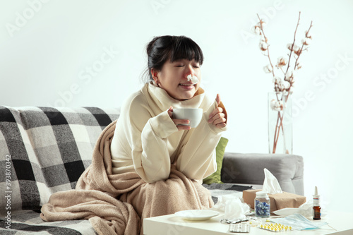 Breathe. Young woman wrapped in a plaid looks sick  ill  sneezing and coughing sitting on sofa at home indoors. Healthcare and medicine  ill prevention  seasonal illness symptoms and self-protection.