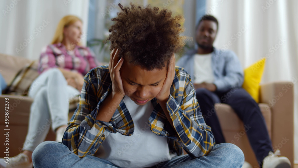Desperate african american boy during parents quarrel closing ears at home Desperate african american boy during parents quarrel closing ears at home