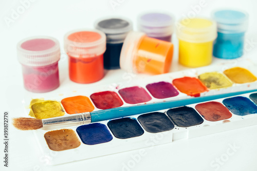 Colorful gouache paints and brush for painting on white background. Copy, empty space for text