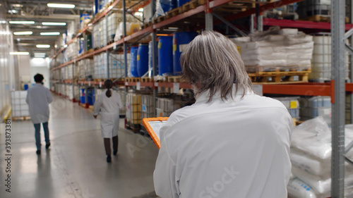 Technicians in white coat walking in modern chemical factory warehouse