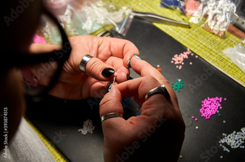 the girl makes beadwork  beading as a hobby. Jewelry made with your own hands.