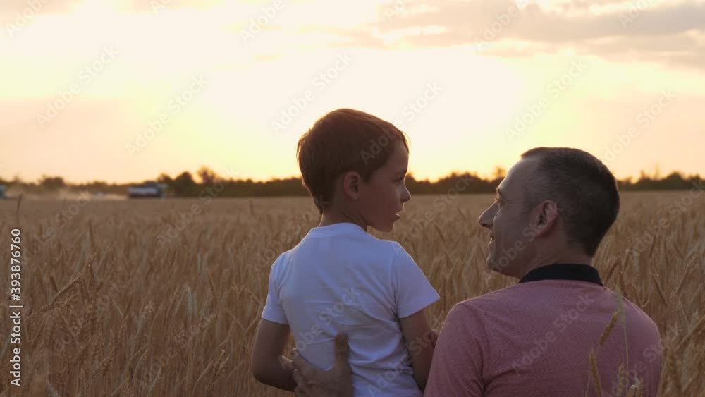 A farmer father shows his son the work of a combine in a wheat field. Grain harvesting, teamwork. Family business. A farmer father shows his son the work of a combine in a wheat field. Grain harvesting, teamwork. Family business.