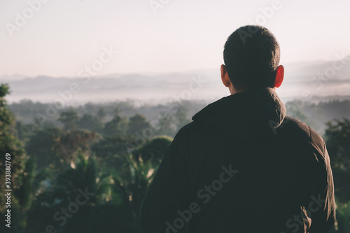 Traveler man looking a sunrise ,fog and landscape on a top of a mountain