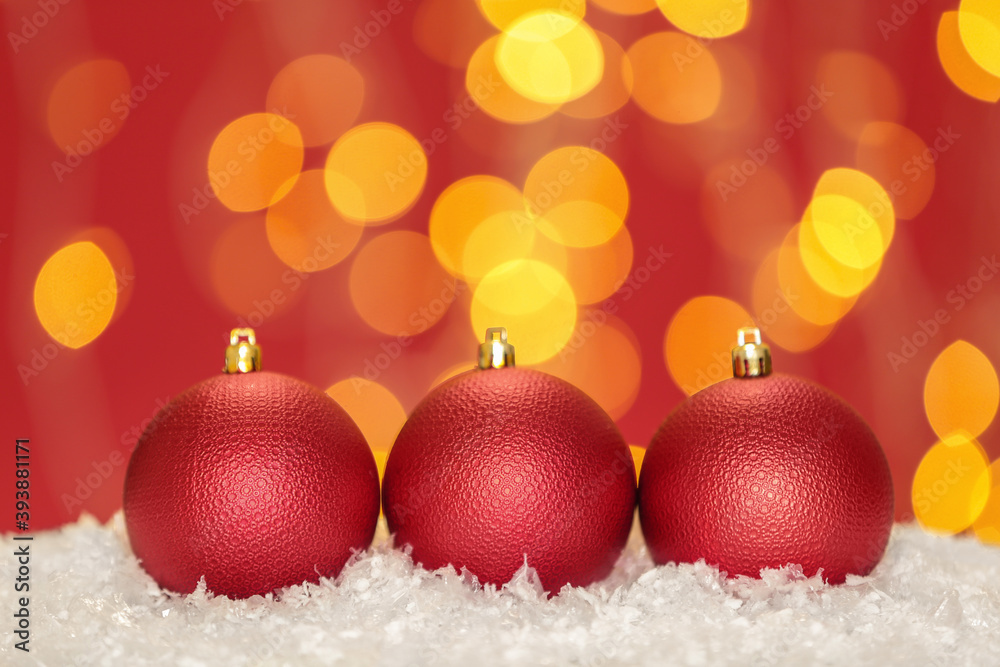Beautiful red Christmas balls on snow against blurred festive lights, space for text Beautiful red Christmas balls on snow against blurred festive lights, space for text
