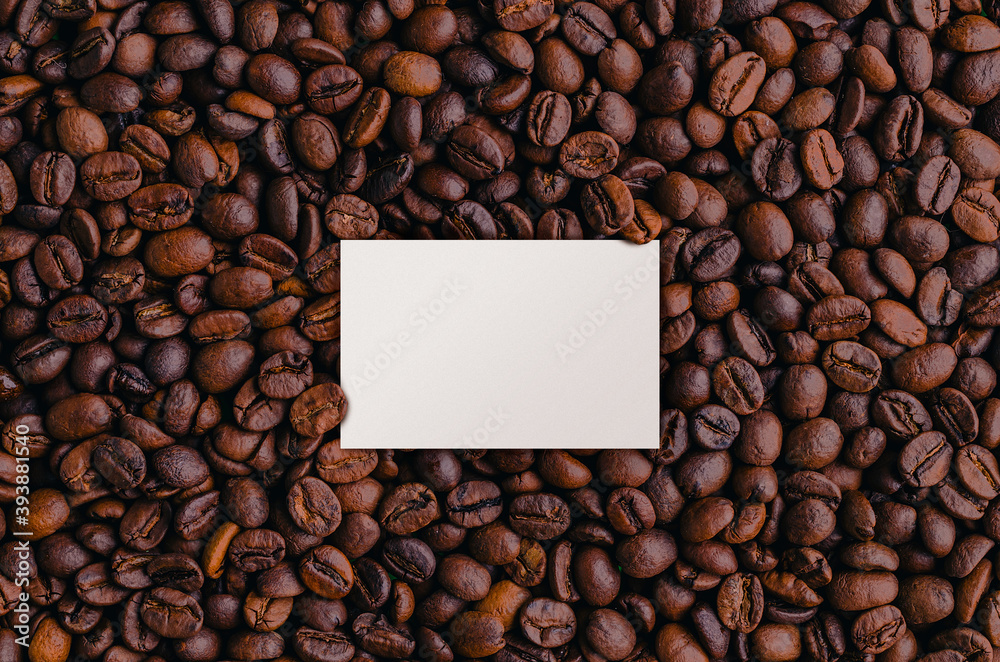 A background of roasted fresh brown coffee beans with a white card mockup A background of roasted fresh brown coffee beans with a white card mockup
