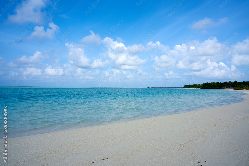 Golden beach under blue sky and clear blue water in the maldives